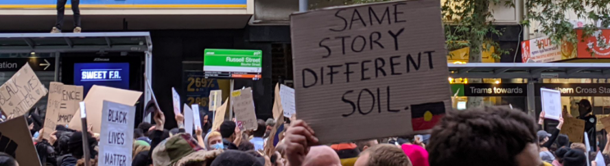 A protester carrying a sign saying Same Story Different Soil in a protest rally against racism in June, 2020